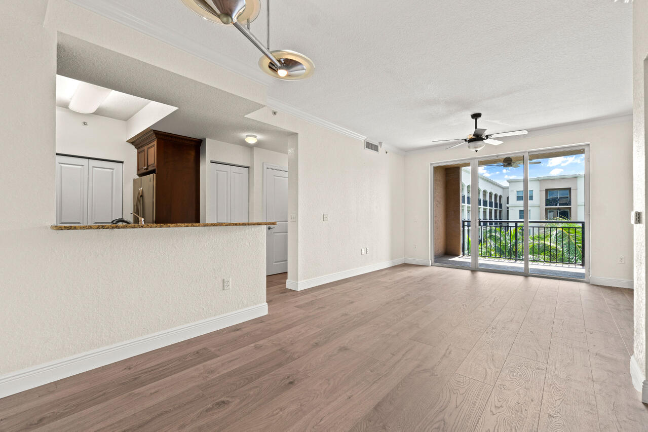 a view of a big room with wooden floor a ceiling fan and windows