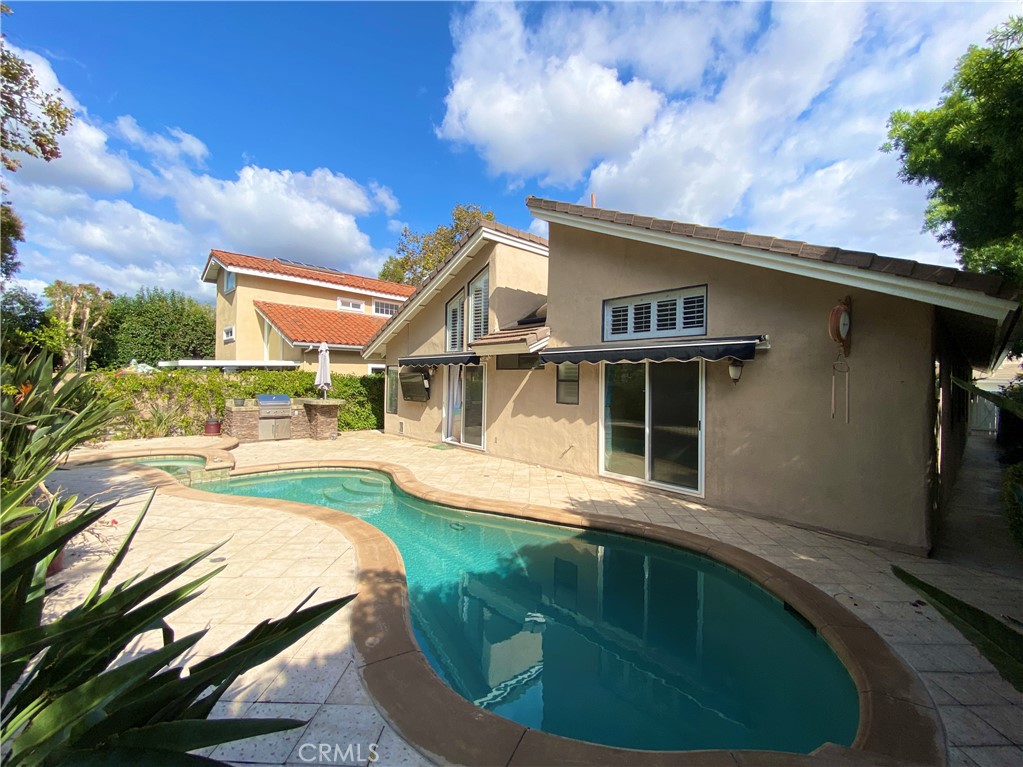 a view of a house with pool and trees in the background