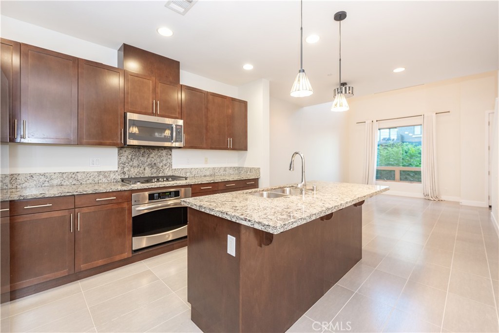 a kitchen with kitchen island granite countertop a stove a sink a center island and cabinets