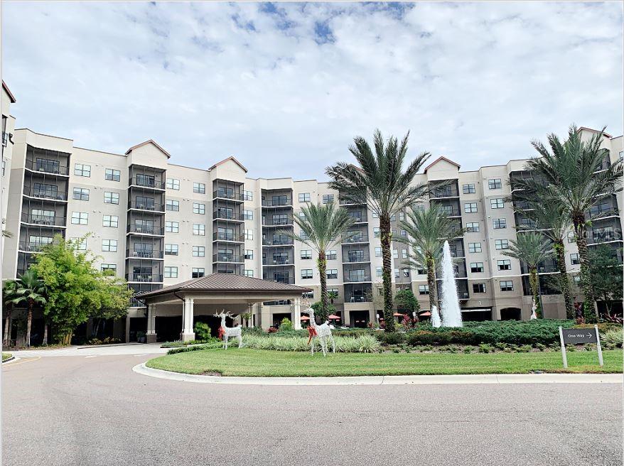 a front view of multi story residential apartment building with yard and trees in the background