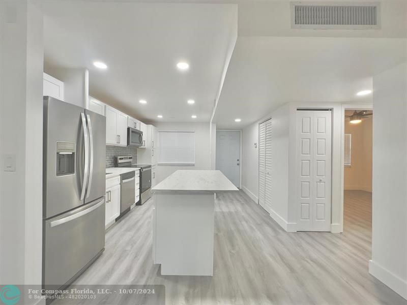 a kitchen with stainless steel appliances kitchen island a refrigerator sink and cabinets