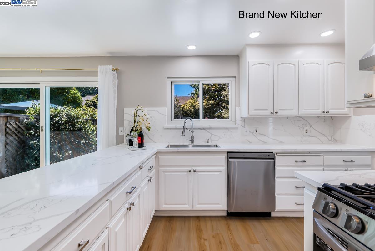 a kitchen with stainless steel appliances granite countertop a sink a stove and a wooden floors