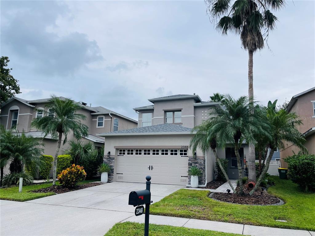 a front view of a house with garden and palm tree