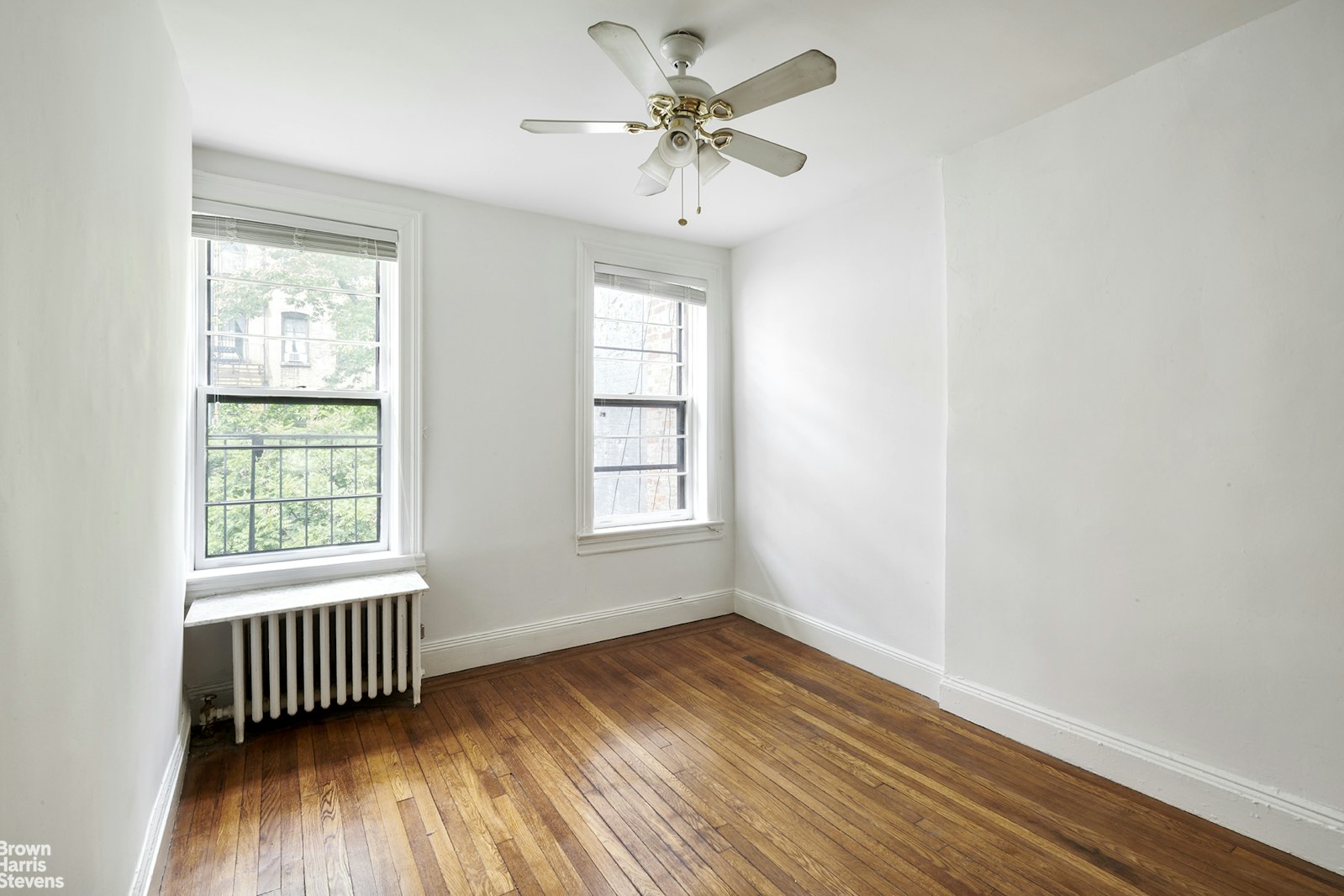 a view of an empty room with a window and wooden floor