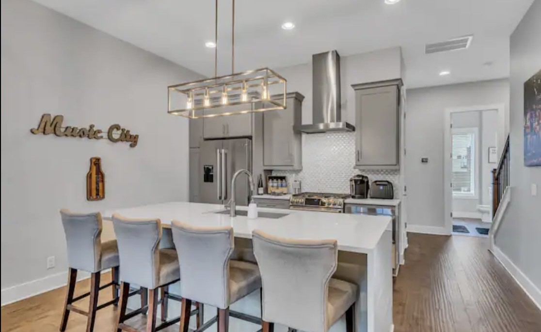 a kitchen with stainless steel appliances a dining table chairs and white cabinets