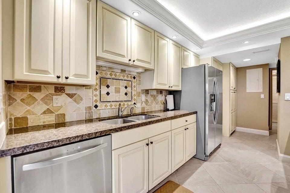 a kitchen with stainless steel appliances granite countertop a sink and dishwasher with white cabinets