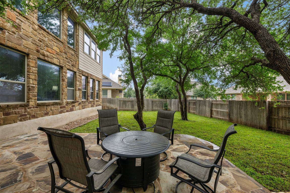 a view of a backyard with table and chairs potted plants and tree