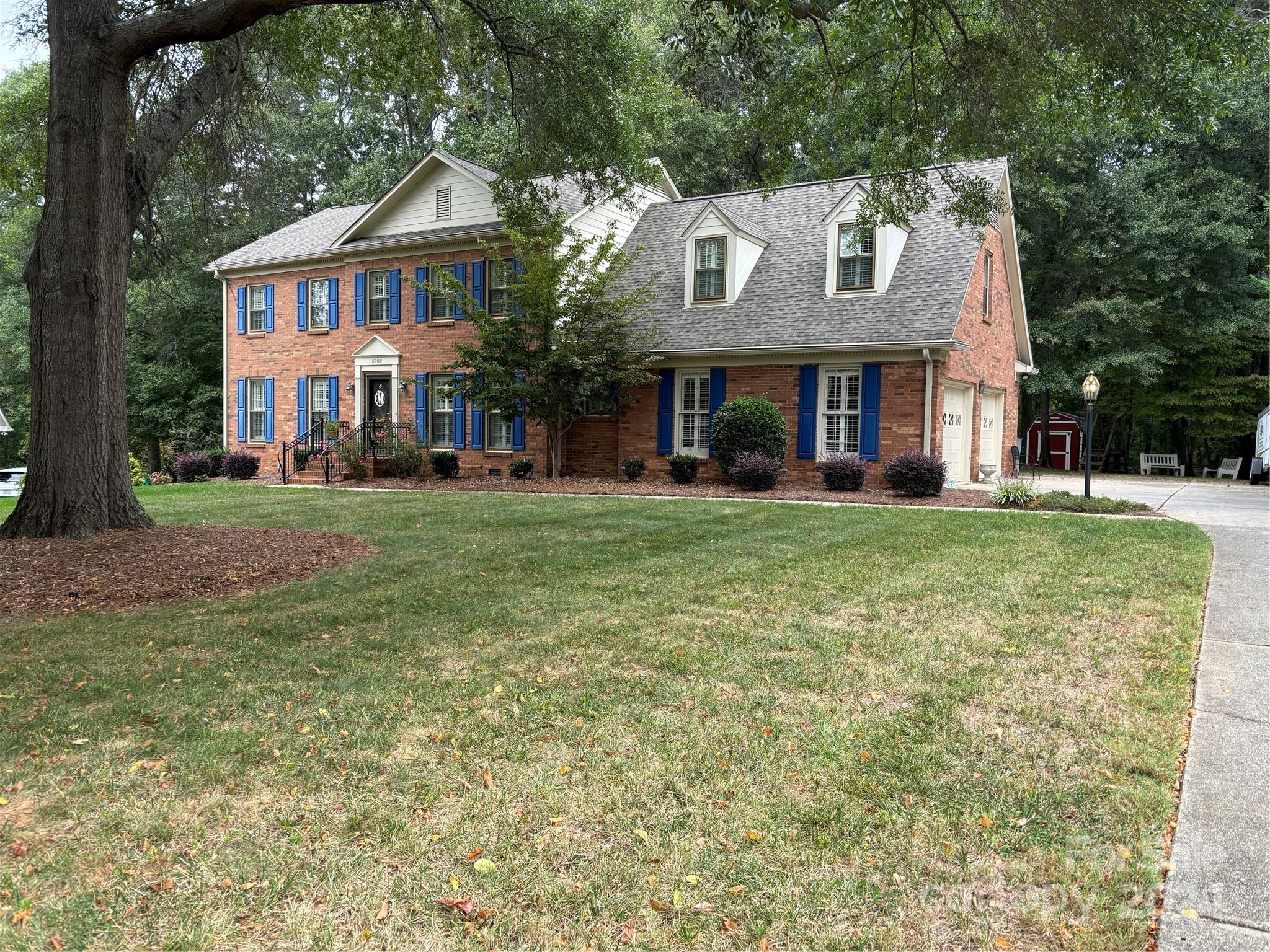 a view of a brick house with a big yard and large trees