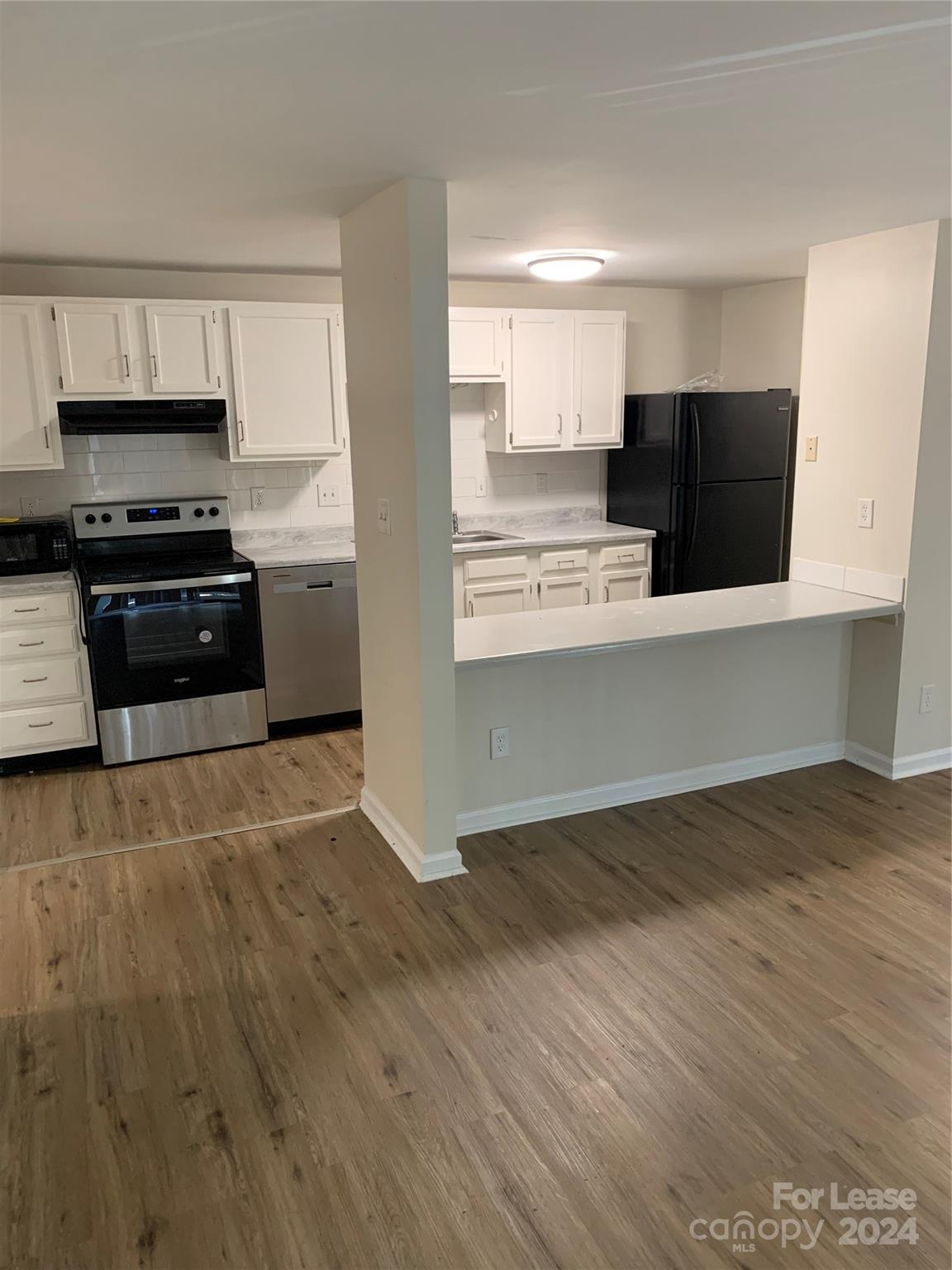 a kitchen with granite countertop a refrigerator and a stove top oven