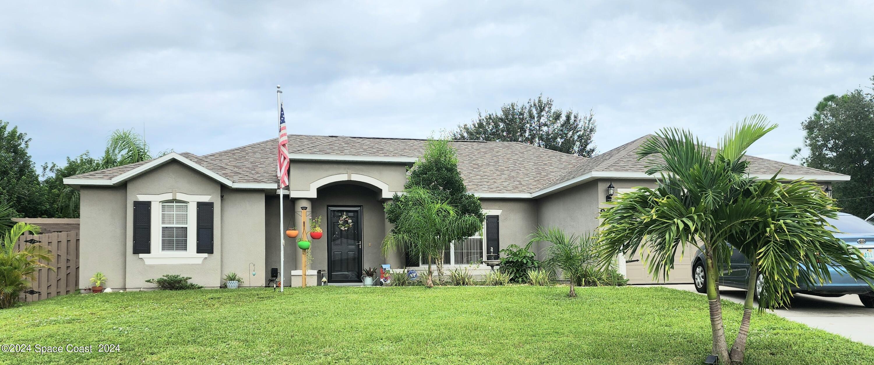 a front view of a house with garden and trees