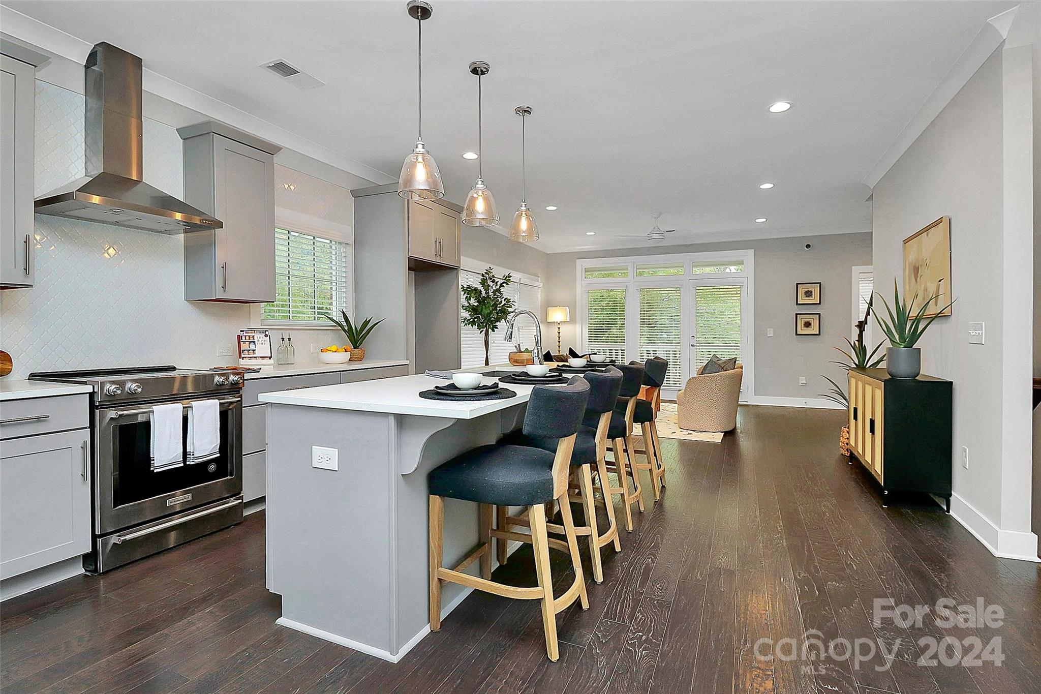 a kitchen with stainless steel appliances a table chairs refrigerator and wooden floor