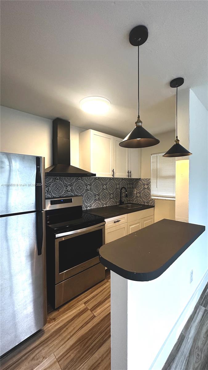 a kitchen with kitchen island a counter a stove a refrigerator and a sink