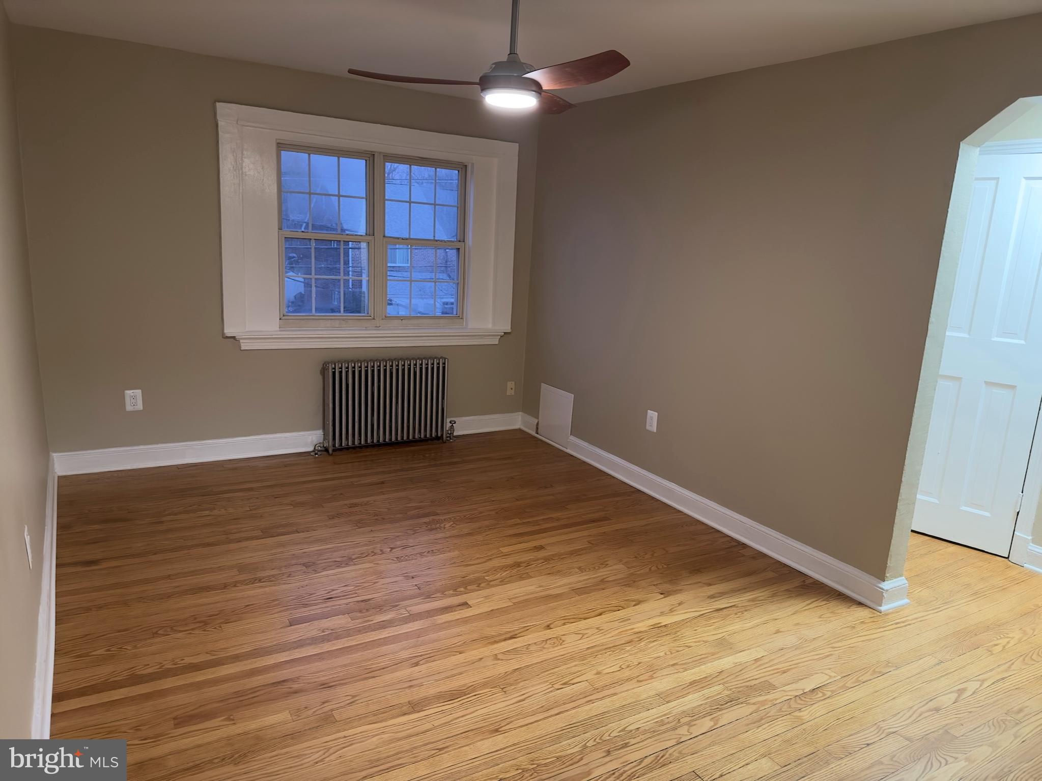 an empty room with wooden floor cabinet and windows