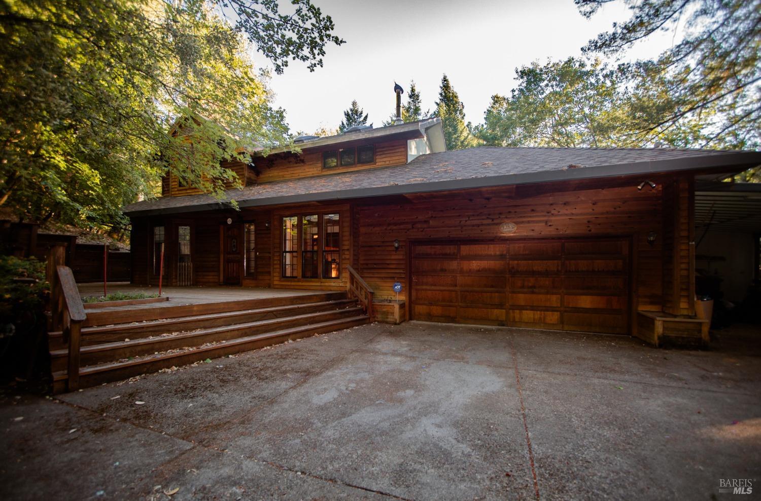 a view of a house with a small yard and a large tree