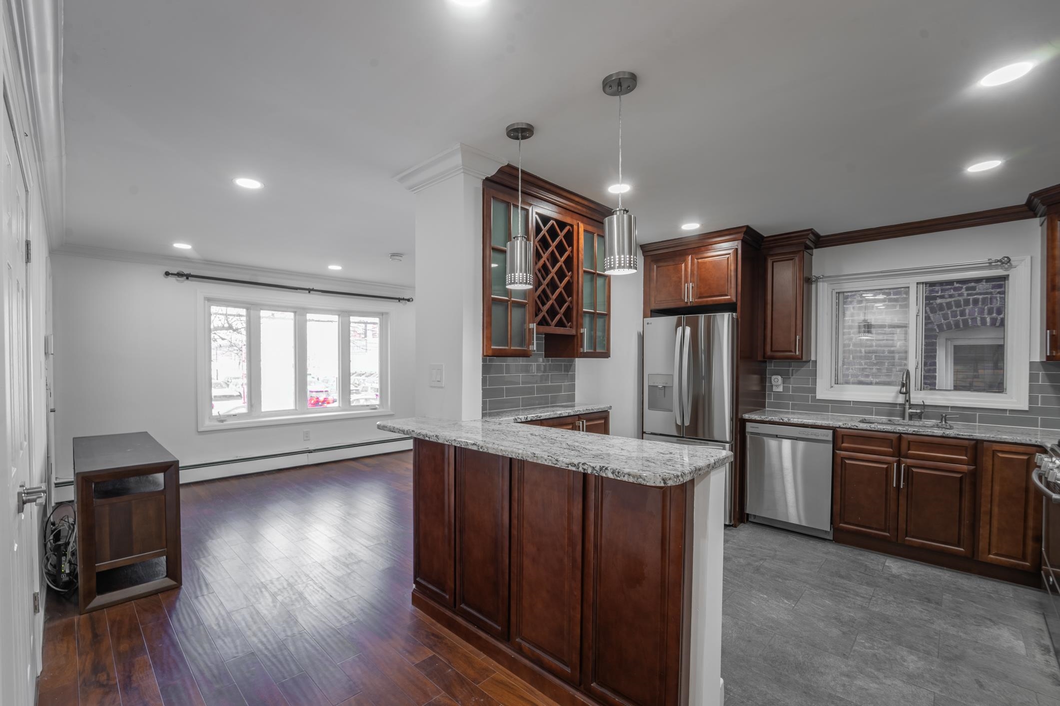 a kitchen with stainless steel appliances granite countertop wooden floors wooden cabinets a sink and a window