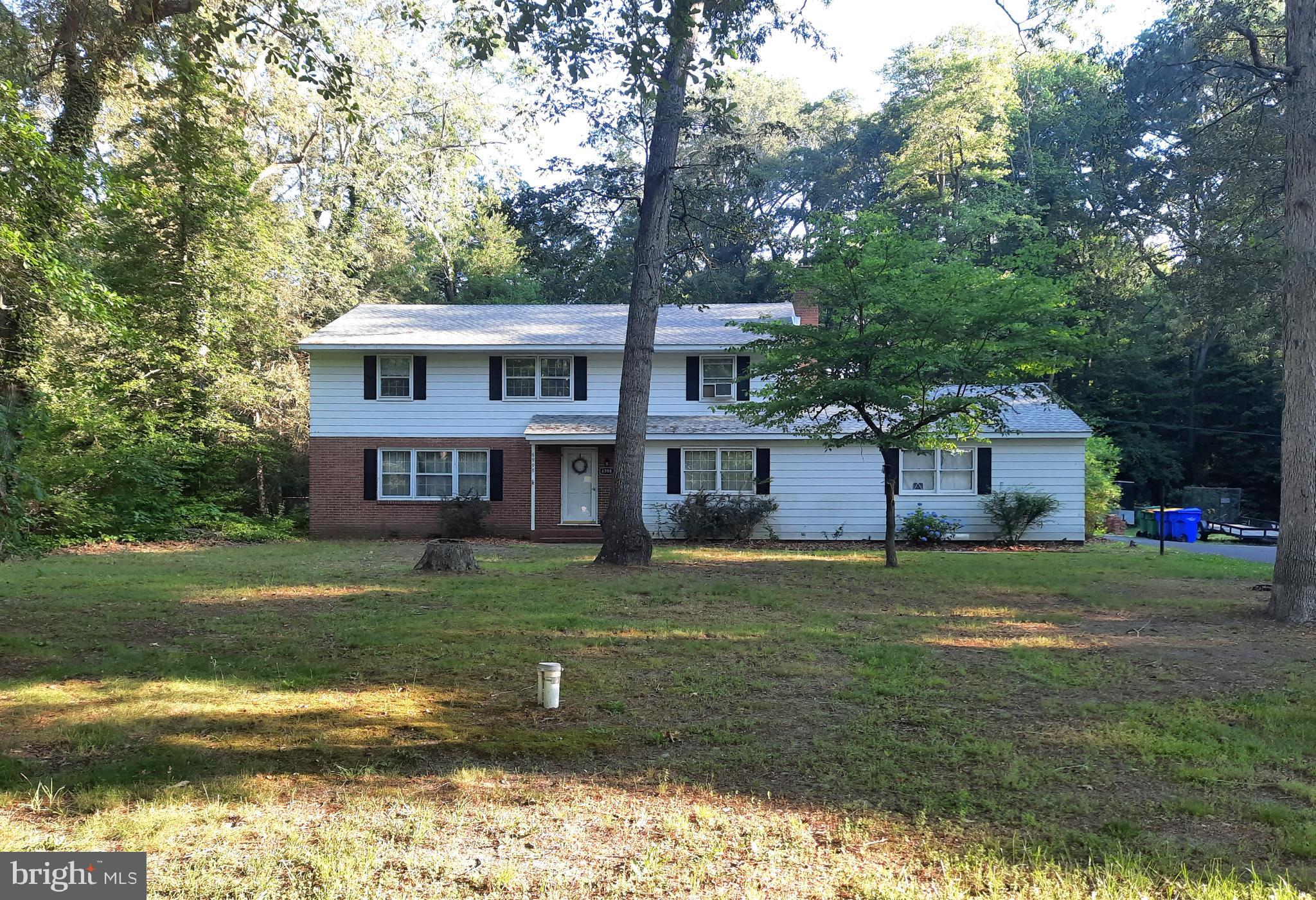 a view of a house with a yard deck and a large tree