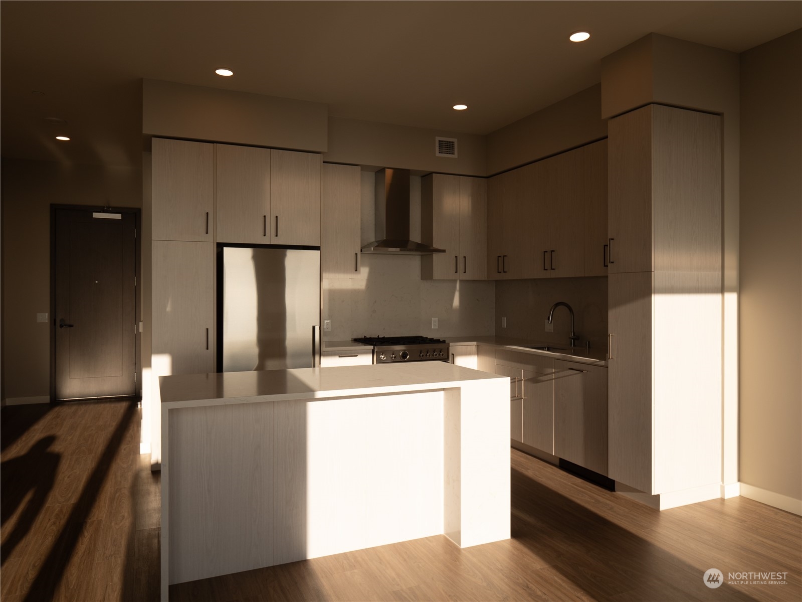 a kitchen with kitchen island a stove a refrigerator and a sink with wooden floor