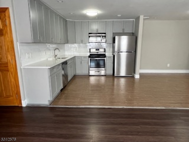 a kitchen with stainless steel appliances wooden floor sink and wooden cabinets