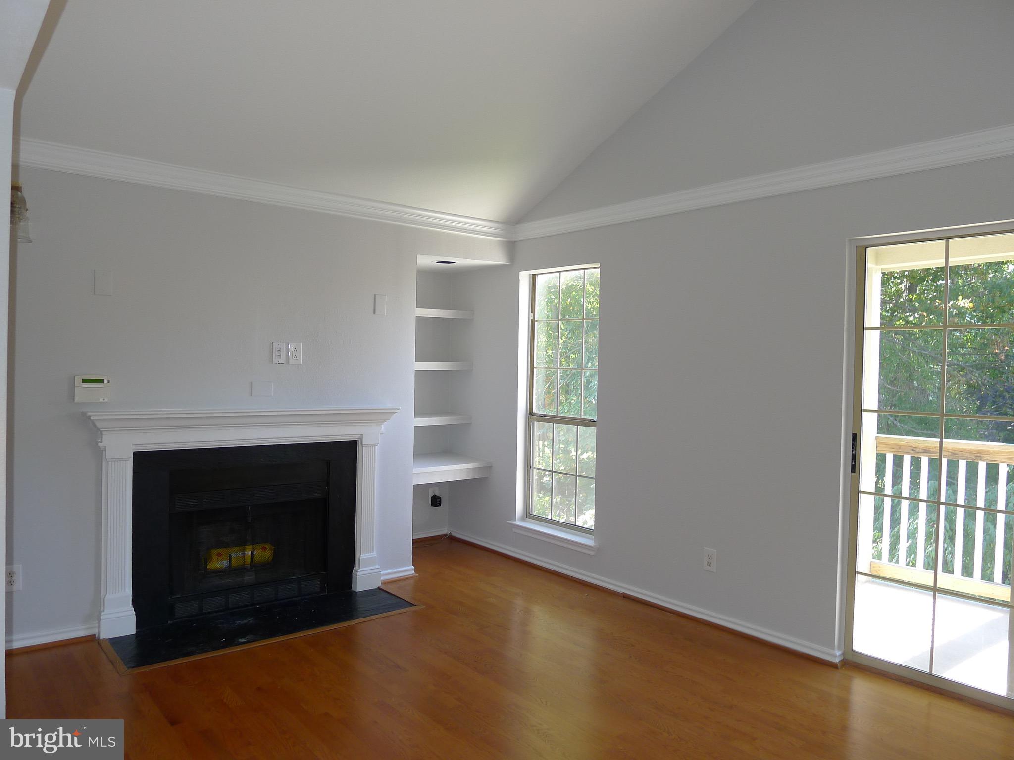 an empty room with windows and fireplace