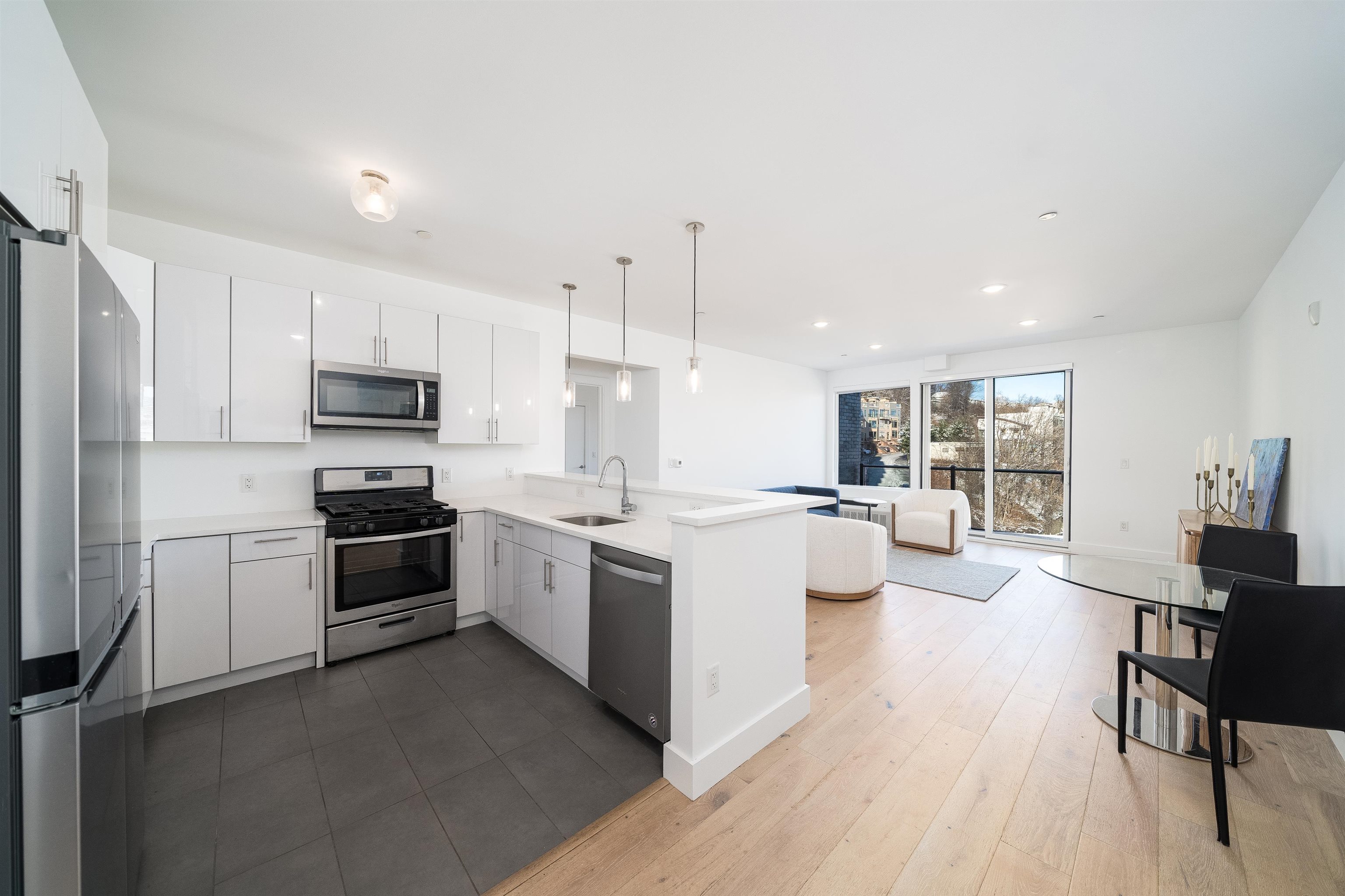 a large kitchen with stainless steel appliances kitchen island granite countertop a stove a sink a refrigerator and white cabinets with wooden floor