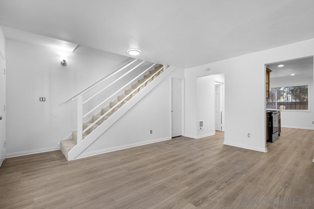 a view of an empty room with wooden floor and a ceiling fan