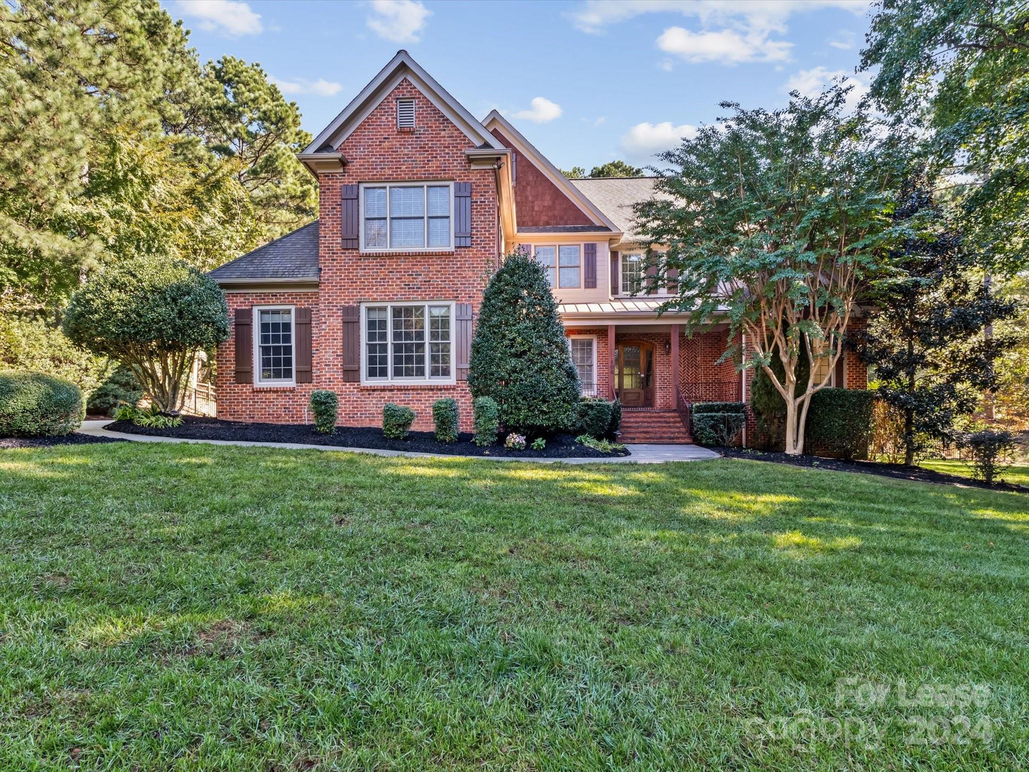 a front view of a house with a yard and trees