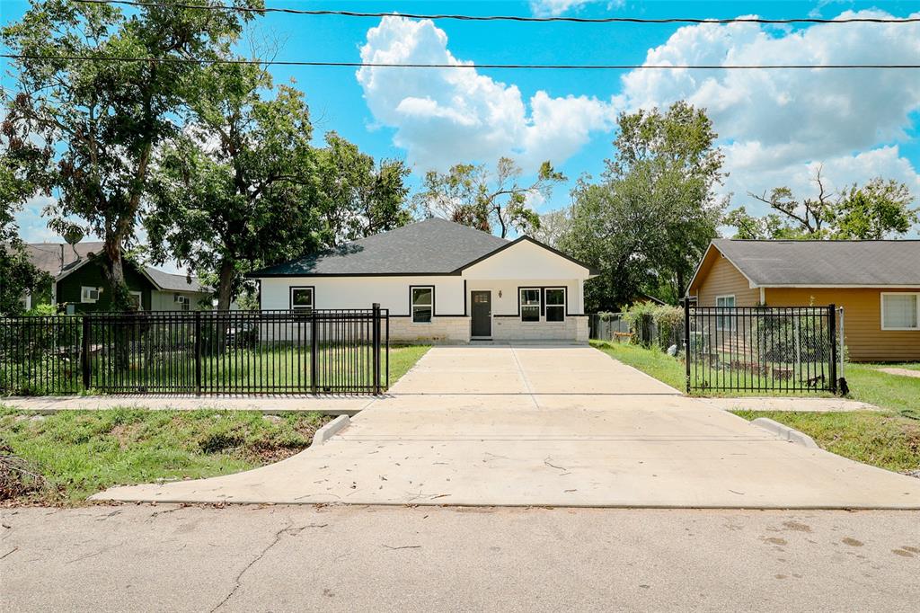 This is a single-story, detached home with a fresh exterior paint job, featuring a fenced front yard and a concrete driveway. The house has a contemporary look with updated windows and a well-maintained lawn, set in a neighborhood with similar style homes.