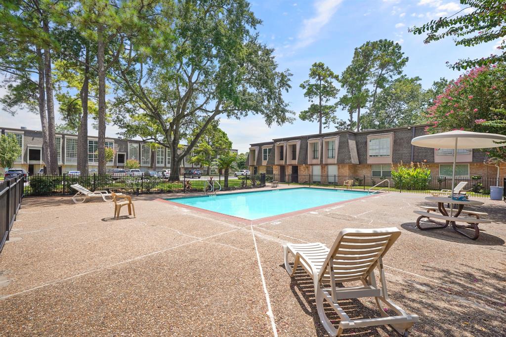 a view of a swimming pool with lawn chairs and wooden fence