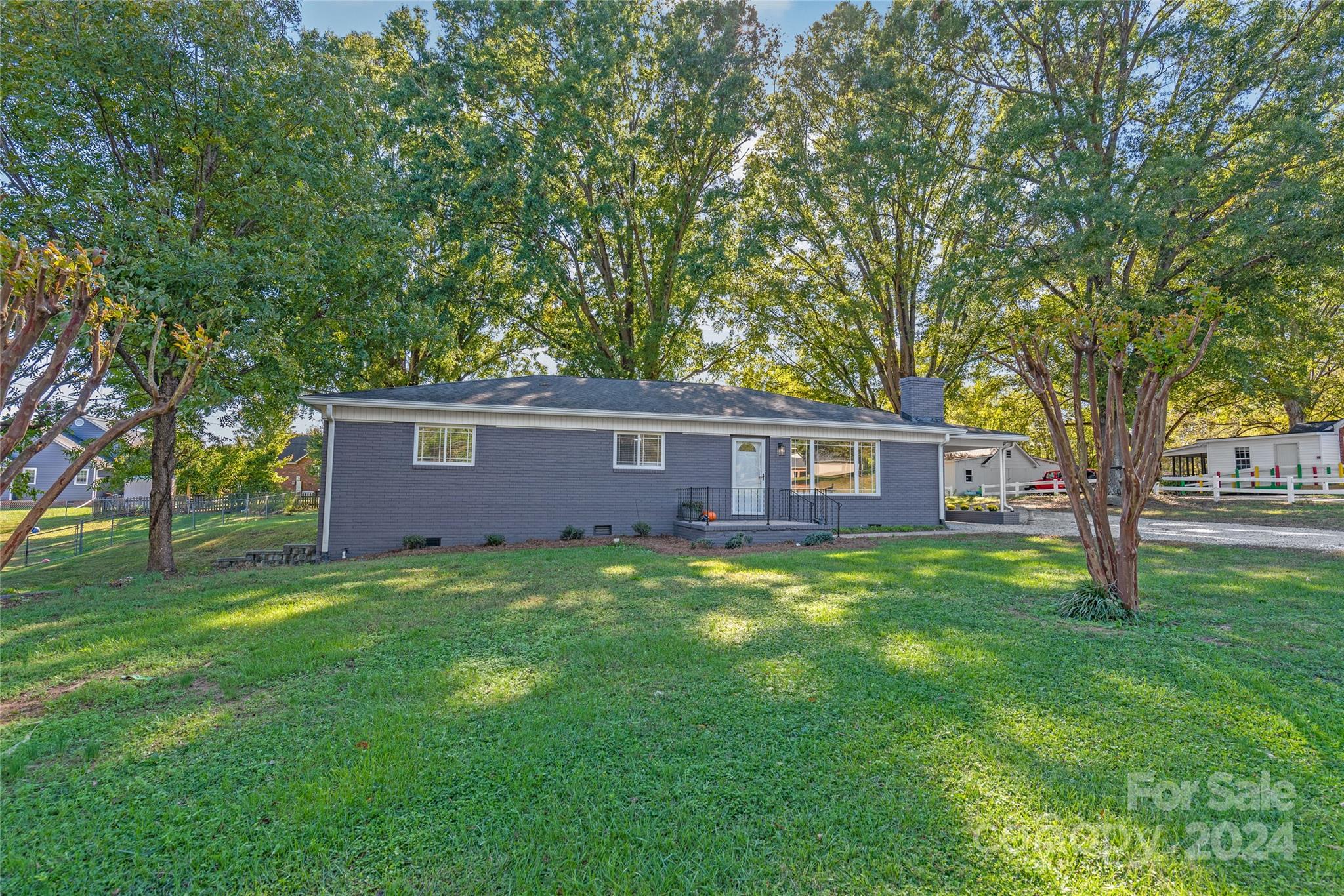 a view of a yard in front of a house with large tree