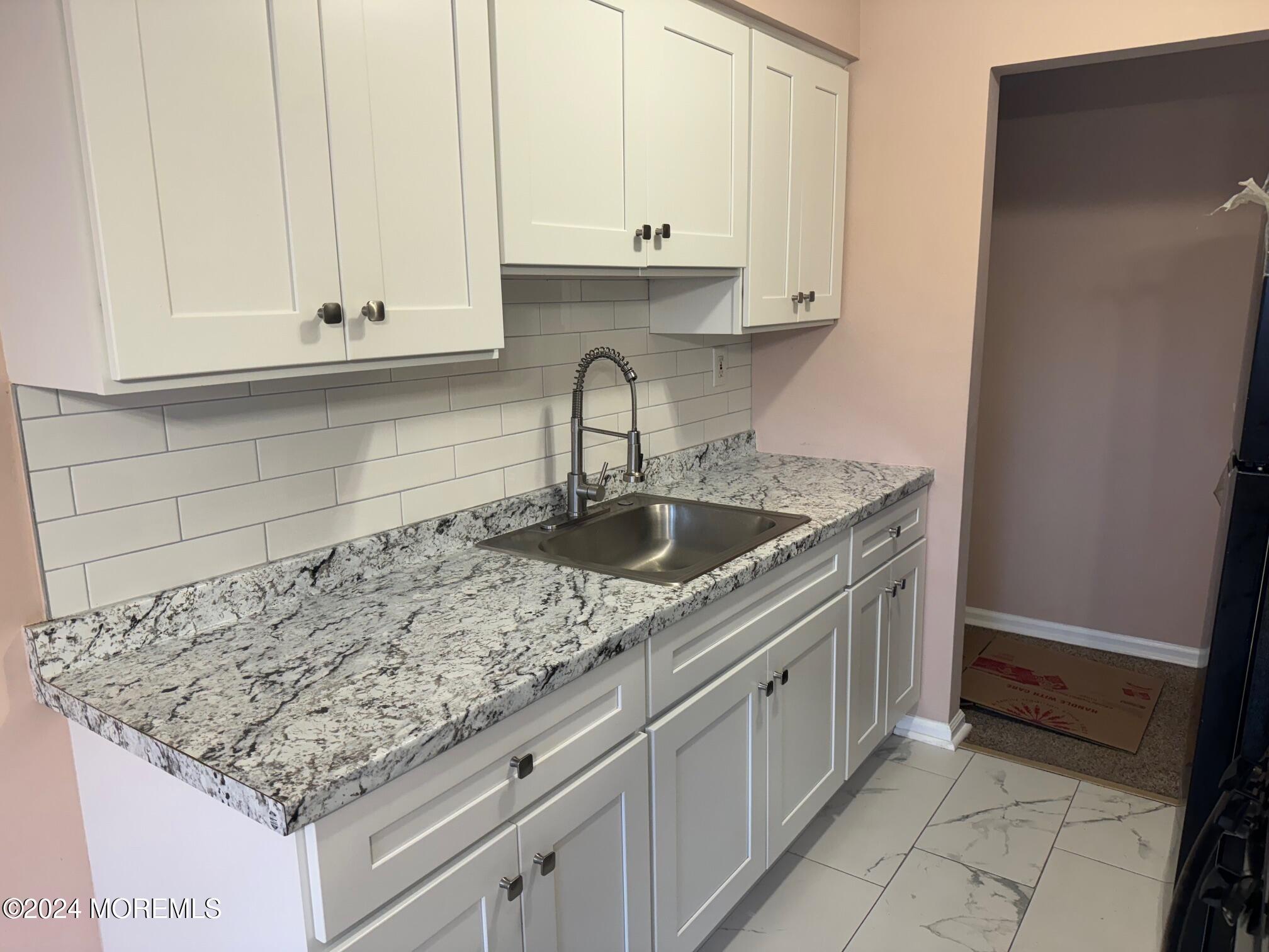 a kitchen with granite countertop a sink and cabinets