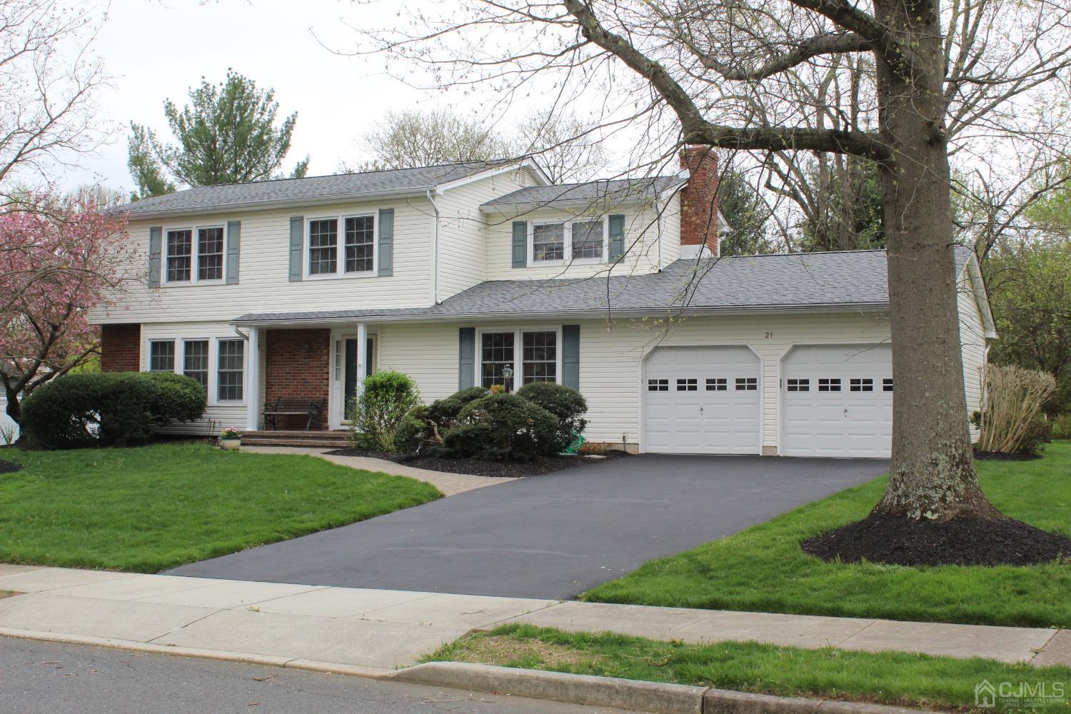 a view of a white house next to a yard with big trees