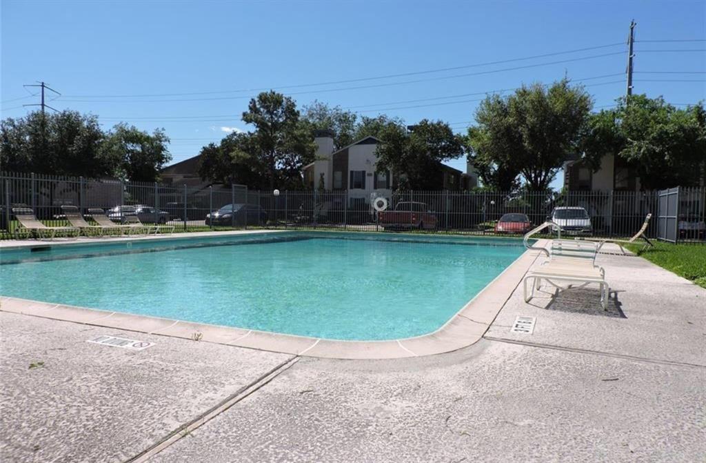 a view of a swimming pool with a yard and palm trees