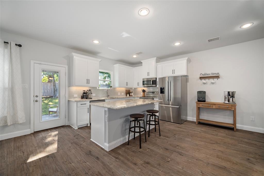 a kitchen with stainless steel appliances a refrigerator a sink a stove a table and chairs