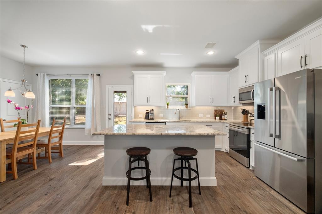 a kitchen with stainless steel appliances granite countertop a dining table chairs refrigerator sink and cabinets