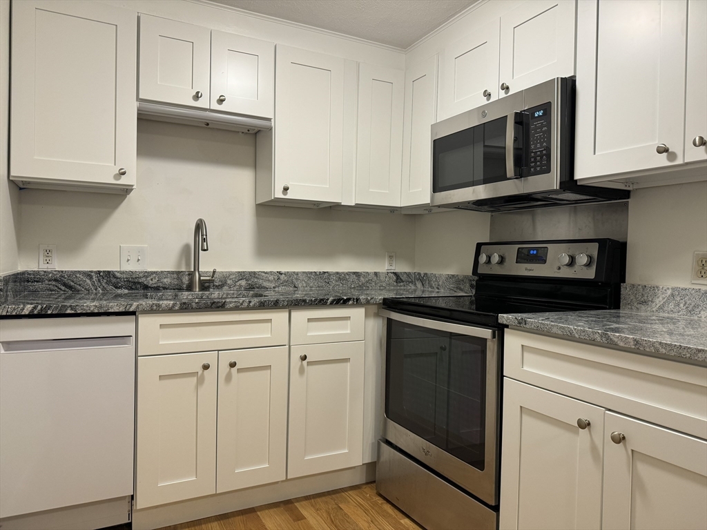 a kitchen with granite countertop white cabinets stainless steel appliances and a sink