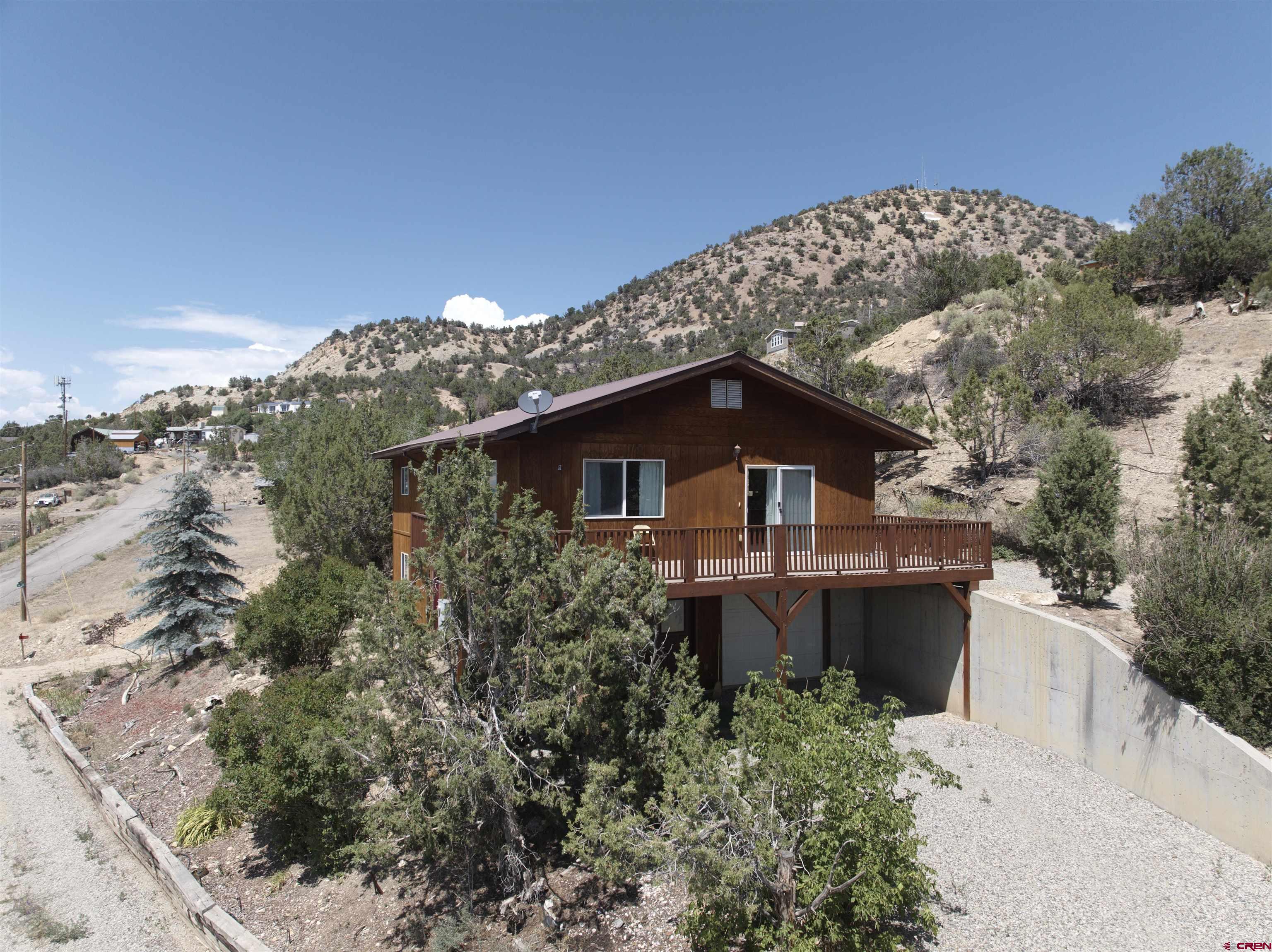 a front view of a house with a yard and mountain view in back