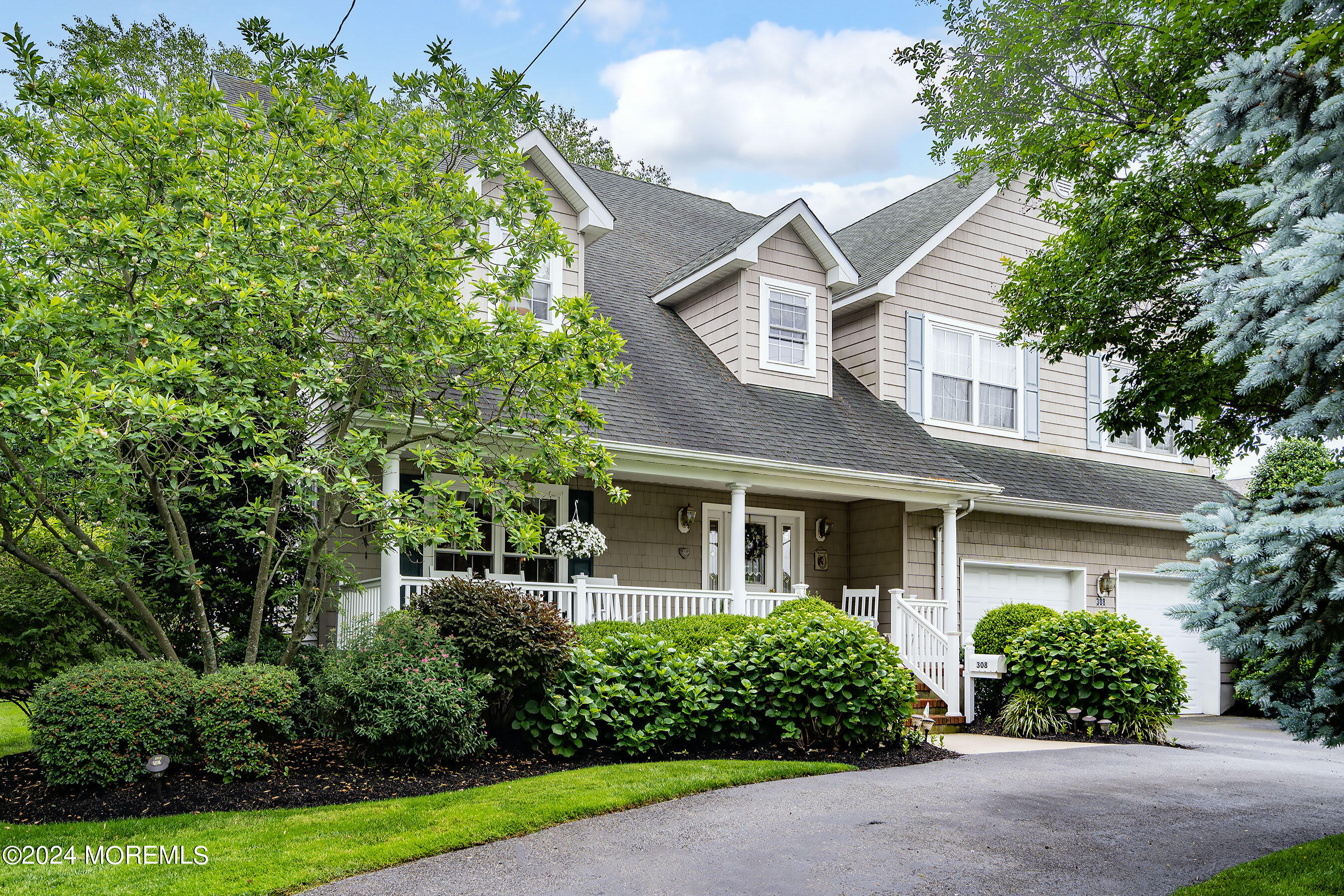 a view of a white house next to a yard with potted plants