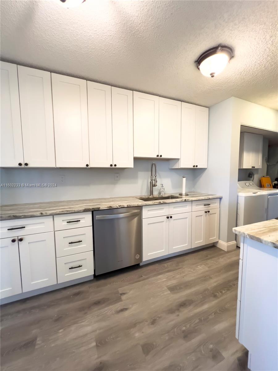 a kitchen with granite countertop white cabinets white stainless steel appliances with a sink and dishwasher