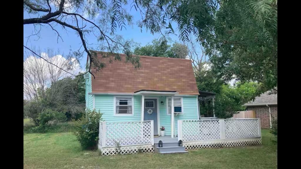 a view of a house with a yard and a large tree