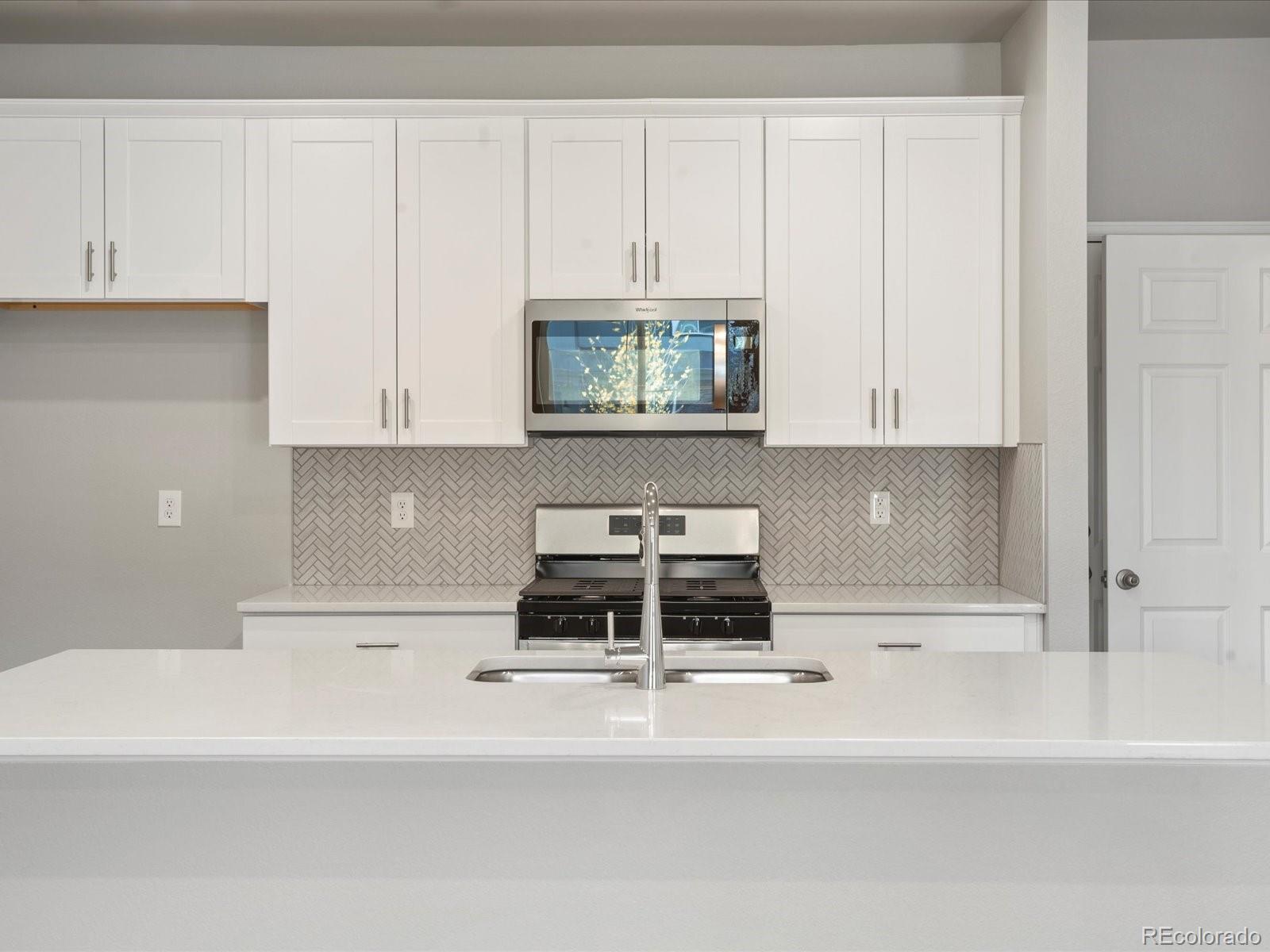 a kitchen with granite countertop white cabinets and stainless steel appliances