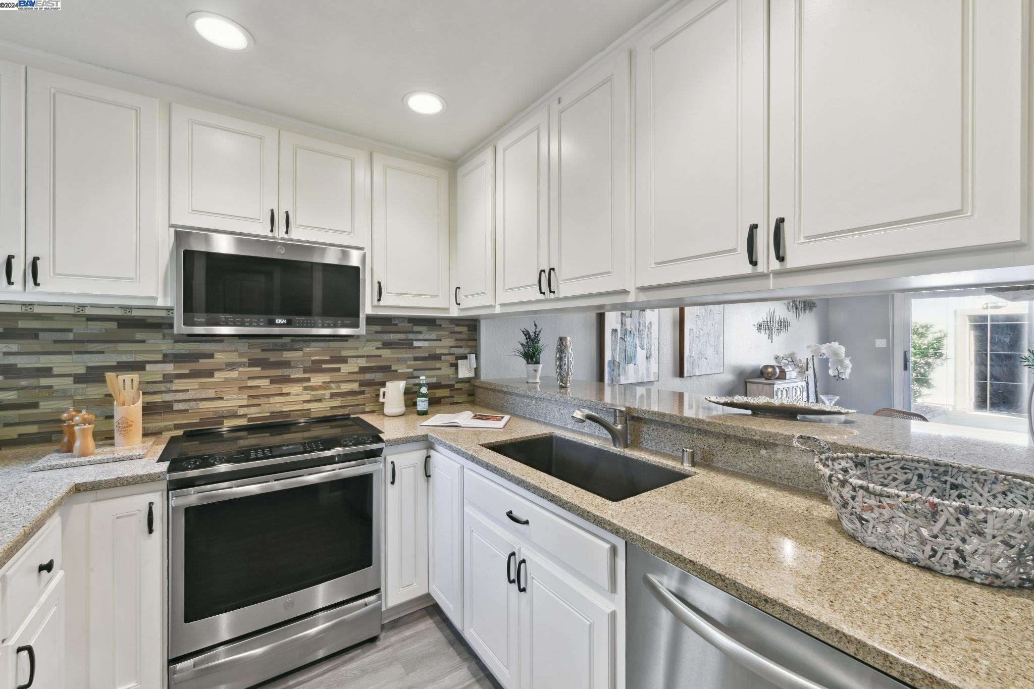 a kitchen with granite countertop white cabinets and stainless steel appliances