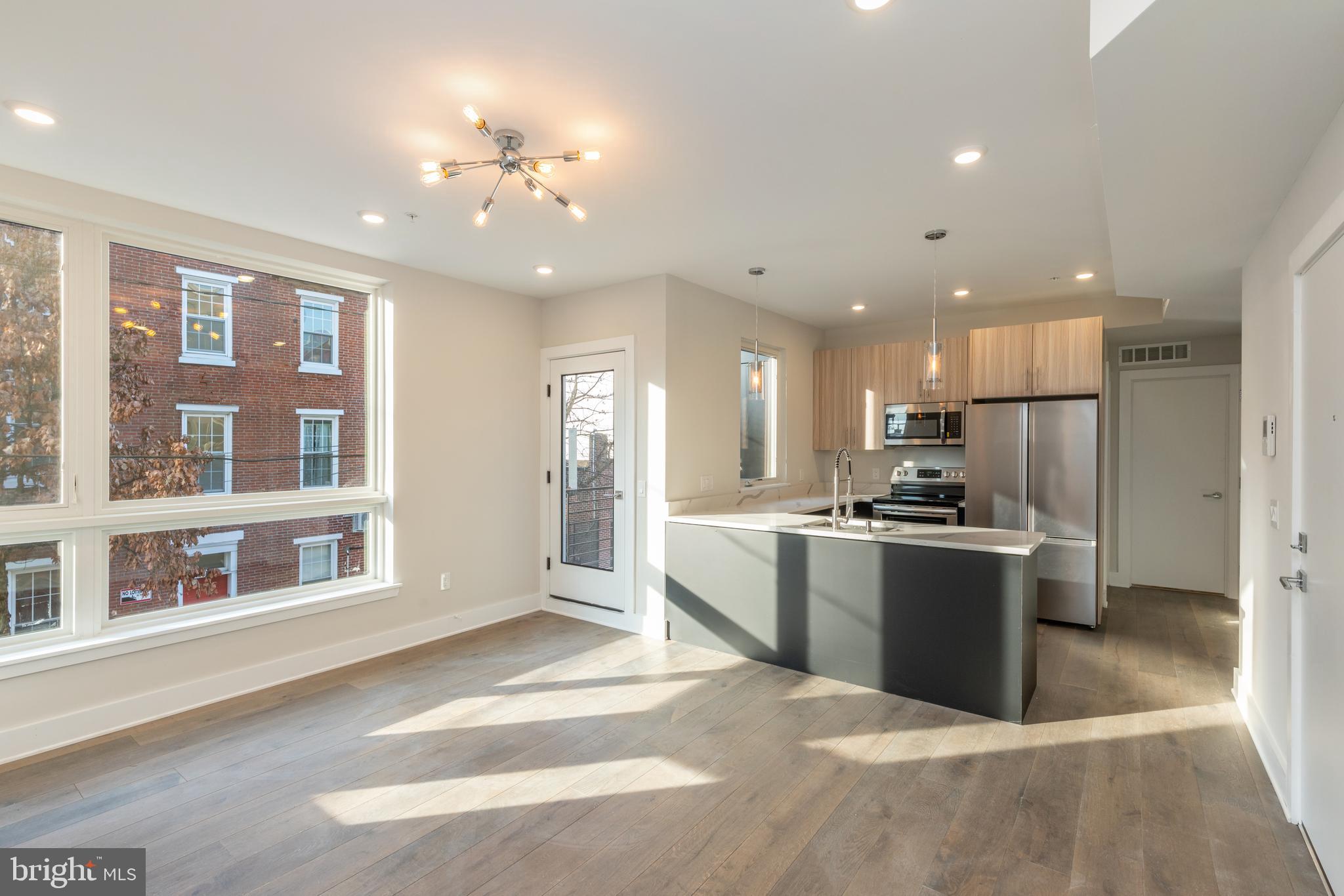 a large kitchen with stainless steel appliances kitchen island a large counter top and a refrigerator