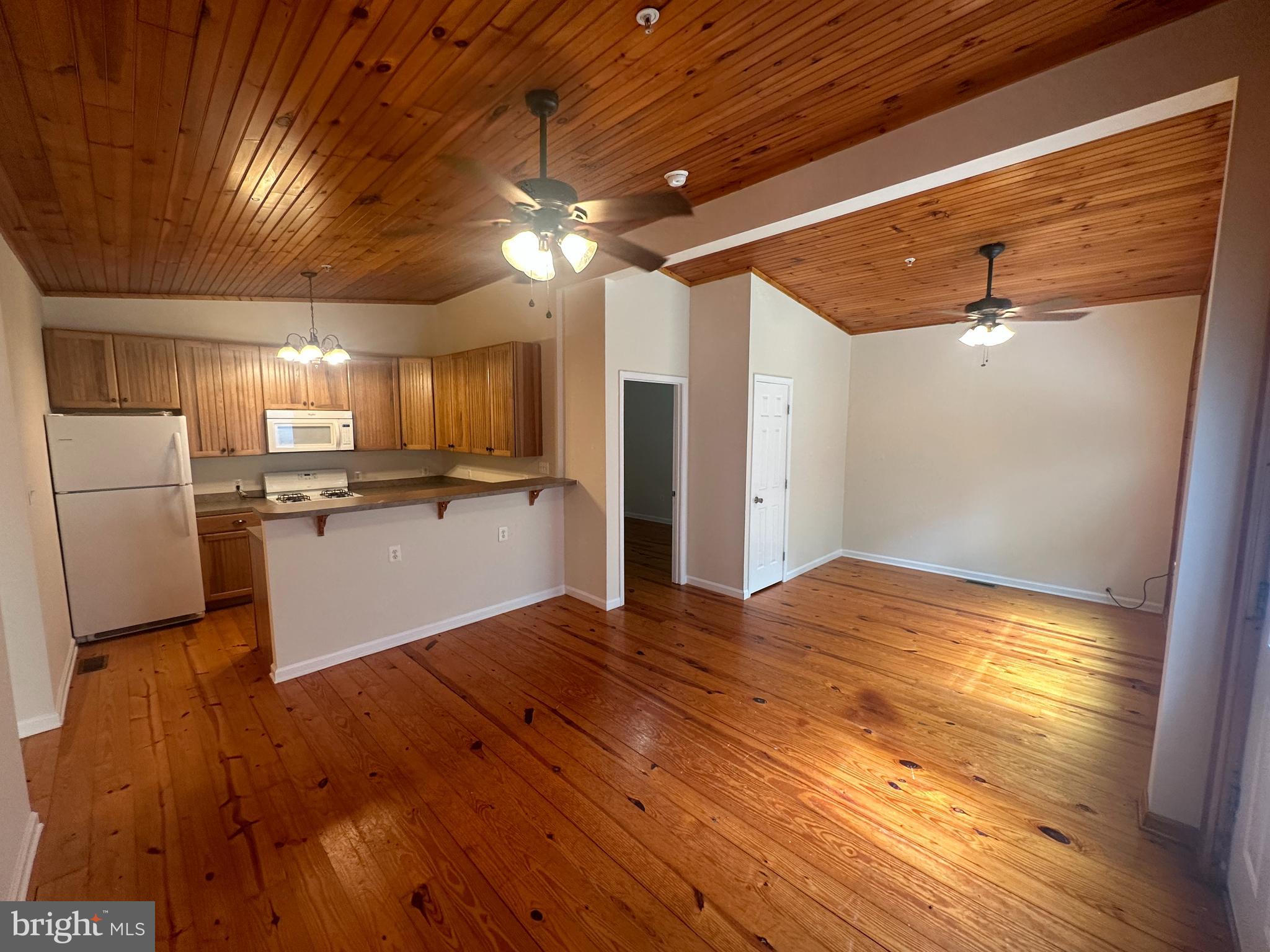 a view of a kitchen with wooden floor and a refrigerator