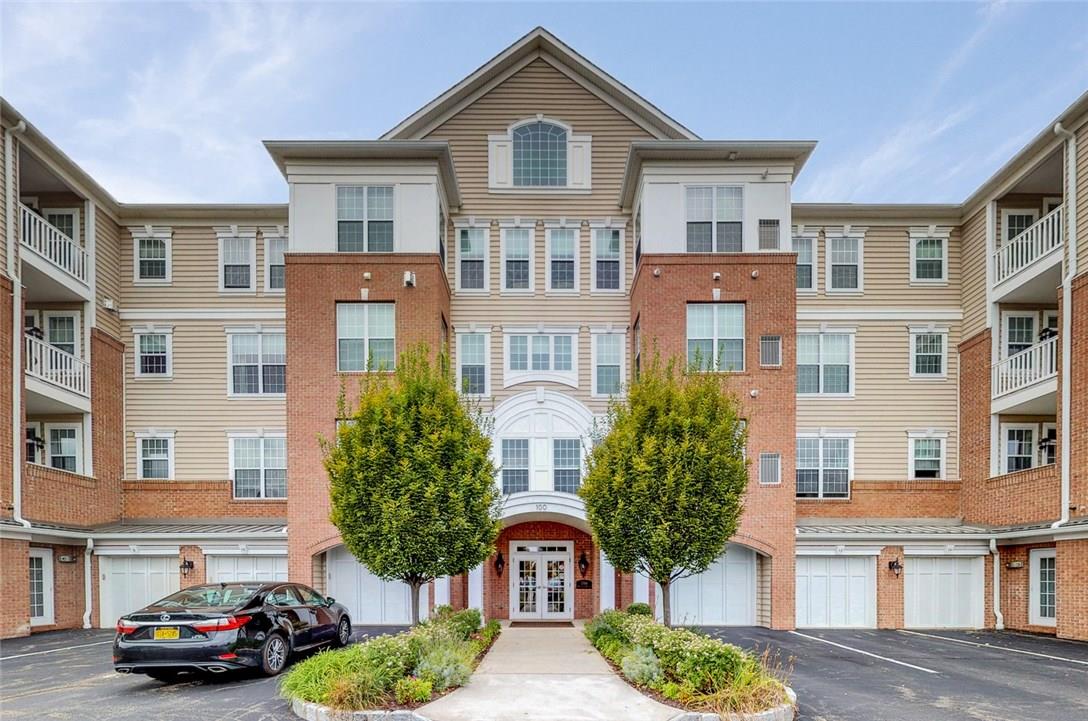 a front view of a residential apartment building with a yard and parking space