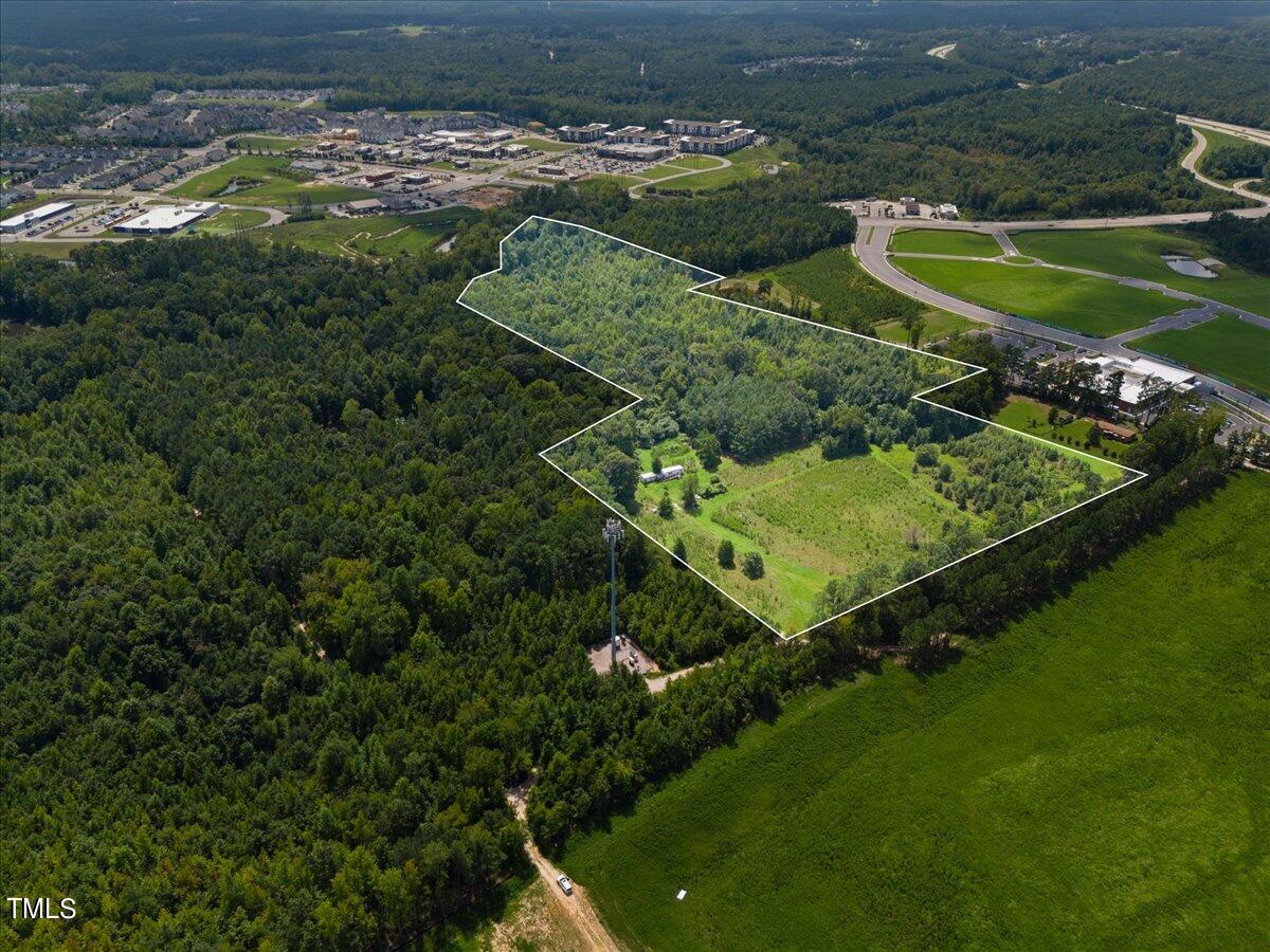 an aerial view of a residential houses with outdoor space and trees all around