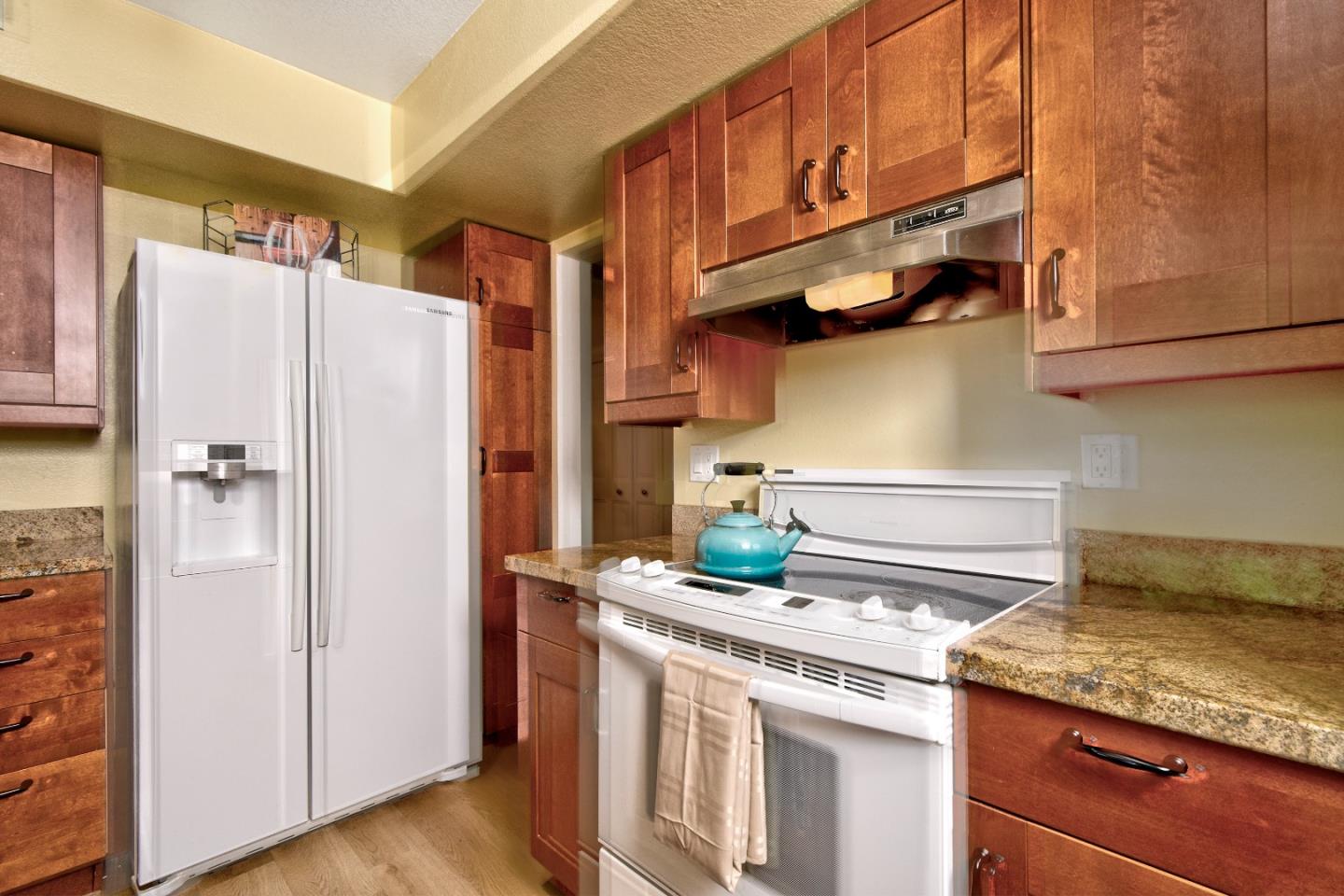 a kitchen with stainless steel appliances granite countertop a refrigerator a stove and a sink with wooden floor