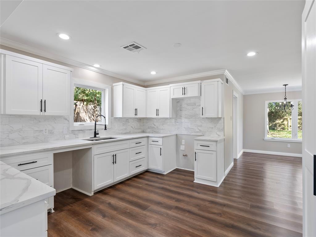 a large kitchen with cabinets wooden floor a center island stainless steel appliances and windows