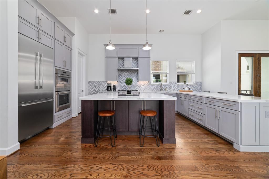 a kitchen with kitchen island granite countertop a sink cabinets and stainless steel appliances