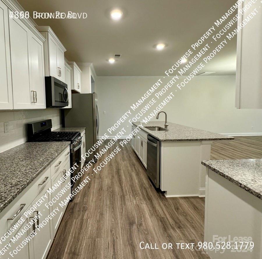 a kitchen with stainless steel appliances granite countertop a lot of counter space and wooden floor