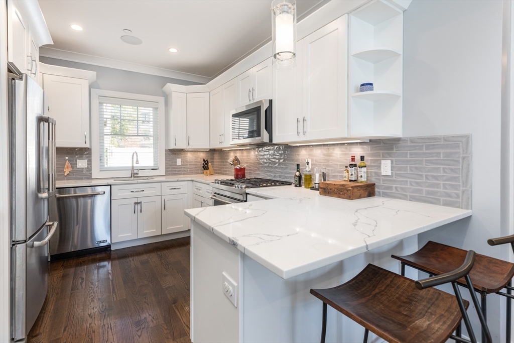 a kitchen with a sink a stove a refrigerator and white cabinets with wooden floor